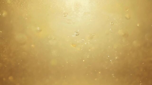 Macro shot of golden bubbles rising in oil or champagne liquid background.