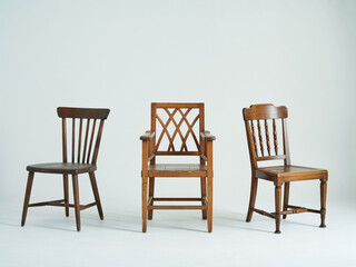 Three antique wooden chairs arranged against a white background