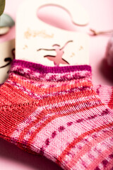 Vibrant pink knitted wool socks are beautifully displayed on a soft surface, highlighting their intricate patterns and cozy texture for winter fashion