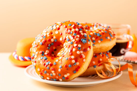Glazed orange donuts with Dutch event Kings day in background. National holiday Koningsdag on 27 April in the Netherlands. Holland culture concept with copy space