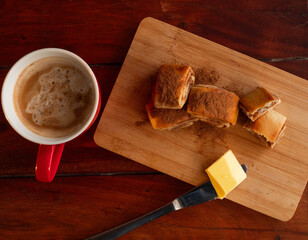 Cozy breakfast with cinnamon rolls, fresh butter and a cup of coffee on a rustic wooden table