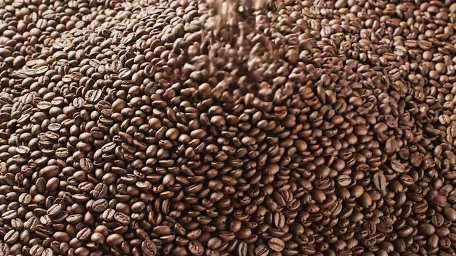 Roasted coffee beans cascading and piling up, filling the frame with rich brown texture