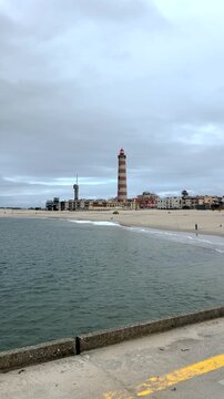 Lighthouse in Aveiro, Portugal. Sailor on the beach in Aveiro. Striped red and white lighthouse in Portugal.