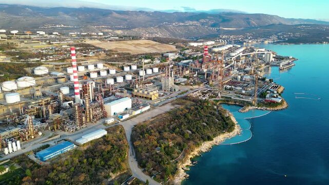 Aerial view of the INA Rijeka Refinery in Urinj, Croatia, nestled along the Adriatic coast with mountains in the background. A blend of industry and natural beauty.
