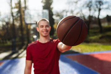Naklejka premium Young Man Holding Basketball On Outdoor Court