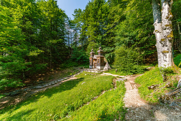 Serene Russian Chapel nestled in lush Soca Valley forest with golden sunlight filtering through ancient trees