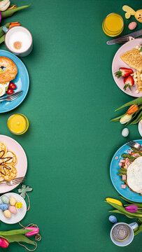 Colorful Easter breakfast spread with pancakes, eggs, and fresh fruits on green background with copy space
