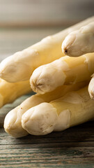 Fresh white asparagus spears stacked on rustic wooden table showcasing natural textures