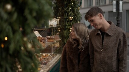 A romantic couple window shopping at a patisserie in Paris France admiring the pastries and...