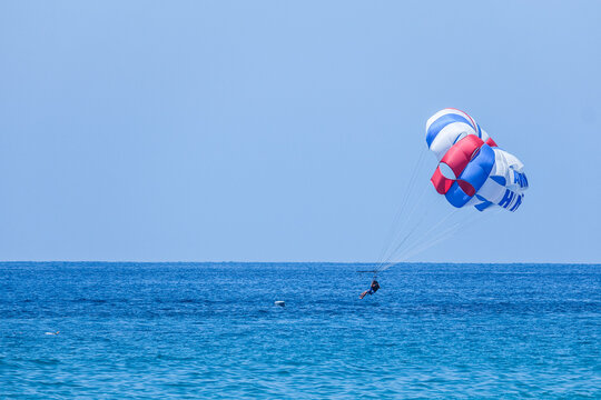 Man parasailing over blue sea with parachute. Summer extreme sport and travel on vacation. Leisure activity in Turkey.