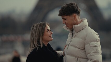 Obraz premium A young couple in love enjoys a romantic moment in Paris France with the Eiffel Tower in the background. This image is perfect for illustrating travel tourism romance and relationships.