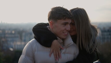 A young couple embraces with the Paris cityscape in the background The man and woman are enjoying...