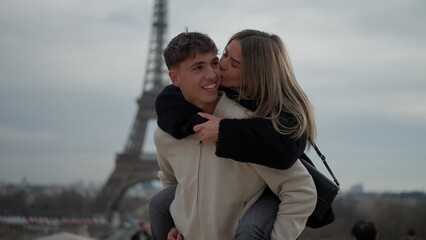 A romantic couple enjoys a piggyback ride in Paris France with the Eiffel Tower in the background...