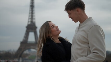 A romantic young couple embraces in Paris France with the Eiffel Tower in the background. This image is perfect for illustrating themes of love travel and European vacations. © 4kclips