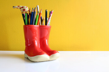 Several Colored Pencil in Red Boot with Yellow Background