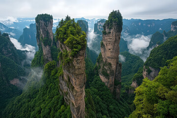 Towering stone pillars rise from lush forested cliffs amid mist and dramatic valley scenery