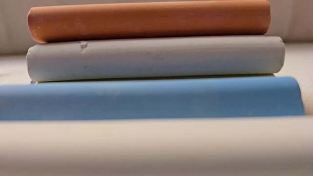 Close-up of vibrant colored chalk pastels stacked neatly on a soft, white textured fabric, showcasing a clean and artistic aesthetic.