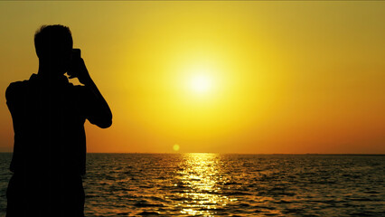 Man Taking Photo Of Sea At Sunset at Sunset
