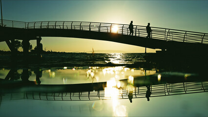 People Walking On Bridge At Golden Hour
