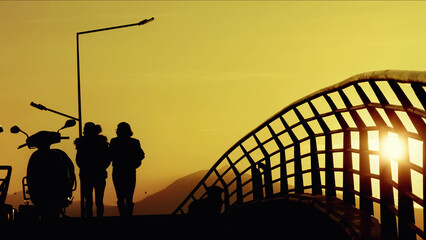 Silhouetted People On Bridge At Sunset