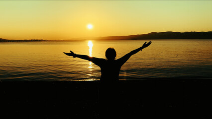 Person Standing Against Golden Sea Sunset
