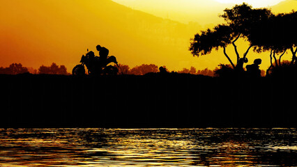 Silhouette Trees And Motorcycle And Calm Sea At Golden Sunset