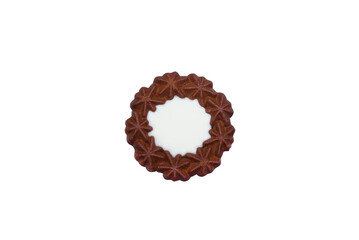 A top-down view of a dark cocoa butter cookie in a decorative star-flower shape, featuring a smooth white vanilla cream filling at its center, isolated on a pure white background