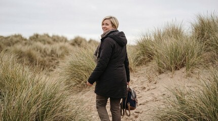 British woman short hair enjoying peaceful walk through coastal sand dunes during quiet seaside getaway
