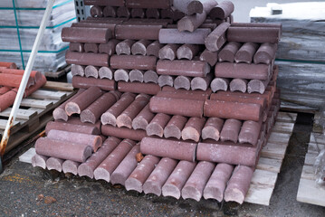 Stack of decorative concrete curb stones on pallets at construction supply yard, ready for landscaping and sidewalk installation.