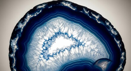Macro cross-section of a blue agate gemstone geode.
A detailed close-up of a sliced agate stone showing intricate blue and white concentric patterns and crystalline structures
