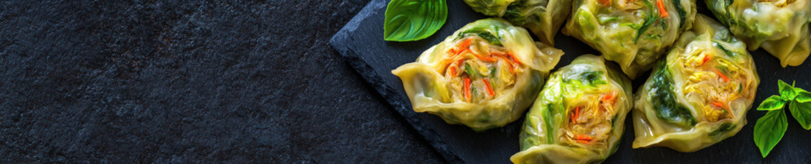 Assorted steamed vegetable dumplings on slate board, top view

