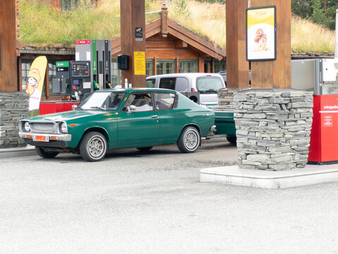 27 july 2025, Norway. Vintage car, oldtimer car Datsun A100 standing at a petrol station in Norway. Vintage technology, 70&rsquo;s design. Other cars in the background. Beautiful retro Japanese car.