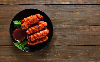 Bacon wrapped sausages with barbecue sauce on plate