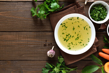 Chicken broth in bowl over wooden background