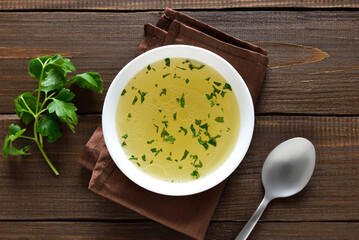 Chicken broth in bowl over wooden background