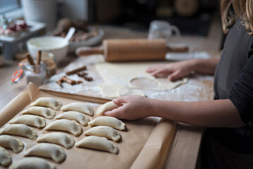 Kneading dough and preparing dumplings as a starchy food for meal. Homemade pierogi making by little girl on table. Traditional cooking.