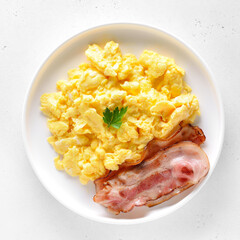 Scrambled eggs and fried bacon on plate