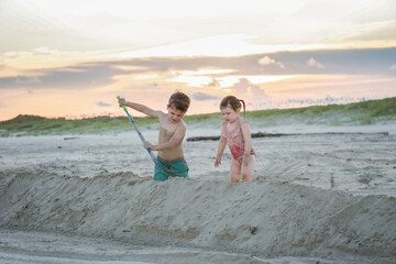 Children playing on sandy beach at sunset