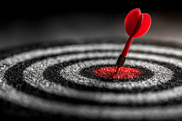 Close-up of a red dart hitting the bullseye on a dartboard, symbolizing focus, precision, and business success with dramatic lighting and shallow depth of field.

