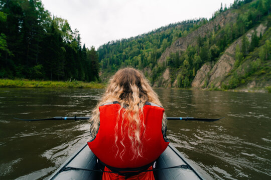 Girl in a life jacket rafting on a packraft on the river