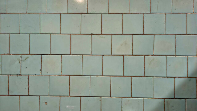 Old green ceramic tiles creating patterned wall surface