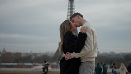 A young couple kisses in Paris France with the Eiffel Tower in the background The romantic scene...