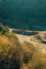 Valley with ancient stone bridge and green vegetation in sunlight. Almogia, Malaga, Andalusia, Spain.