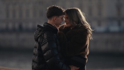 Fototapeta premium A romantic couple in Paris France share a moment of love and affection while wearing winter coats The couple is looking at each other with a building in the background capturing a scene of urban roman