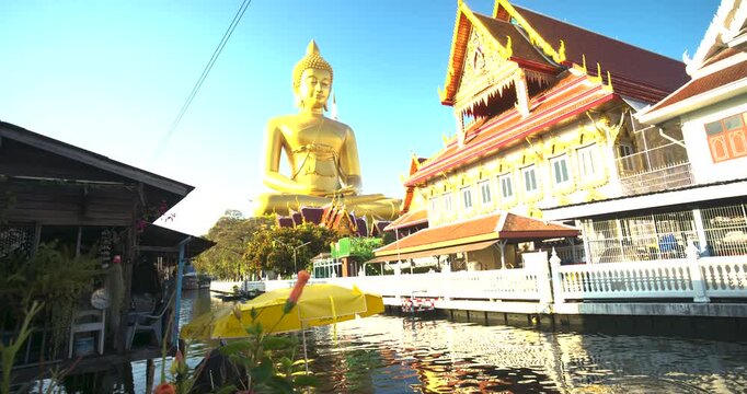 Big Golden Buddha Tep Mongkol Buddha with wooden boat on river at Paknam Bhasicharoen temple or Wat Paknam Bhasicharoen in Bangkok Thailand 