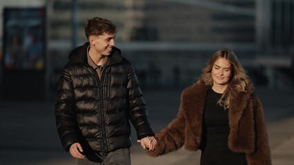 A romantic couple is holding hands and walking in Paris France during golden hour sunlight They are...