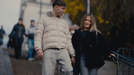 A young couple holds hands while walking down stairs in Paris France The man and woman are dressed...