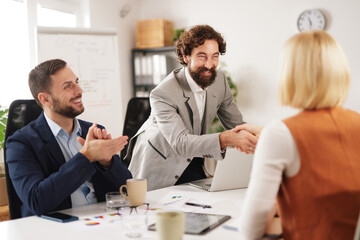 Group of professionals gathers around a table in a meeting room during the day to discuss strategies, brainstorm ideas, and strengthen their teamwork for achieving goals together.