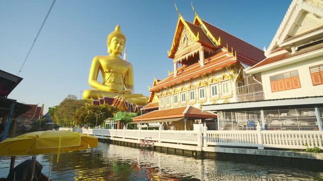 Big Golden Buddha Tep Mongkol Buddha with wooden boat on river at Paknam Bhasicharoen temple or Wat Paknam Bhasicharoen in Bangkok Thailand 