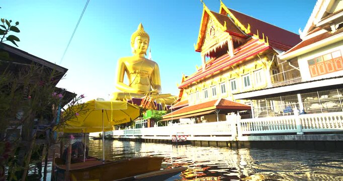 Big Golden Buddha Tep Mongkol Buddha with wooden boat on river at Paknam Bhasicharoen temple or Wat Paknam Bhasicharoen in Bangkok Thailand 